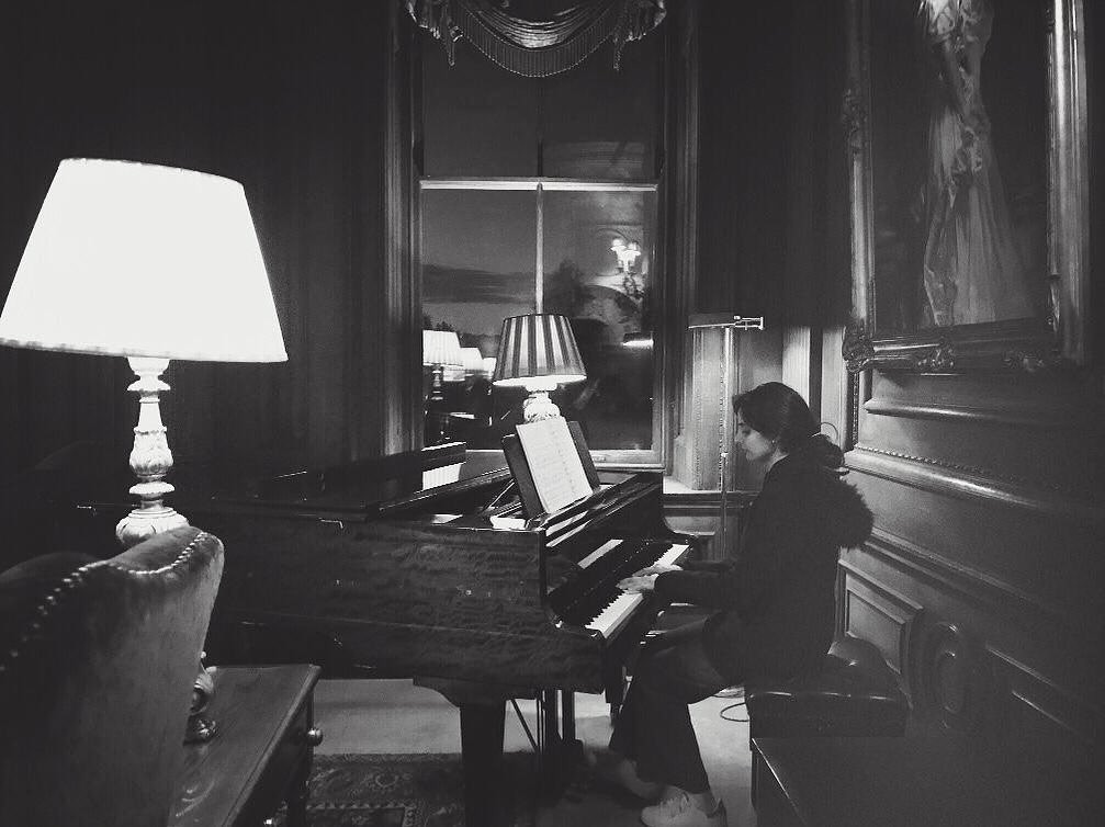 Naina playing a grand piano, black and white