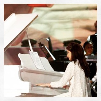 Naina performing at a white grand piano